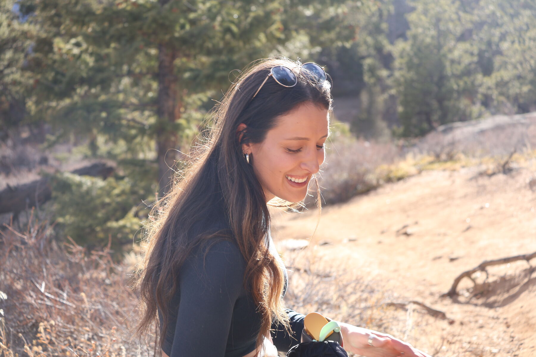 A woman smiling in golden light on a sunlit trail during a natural-light portrait session